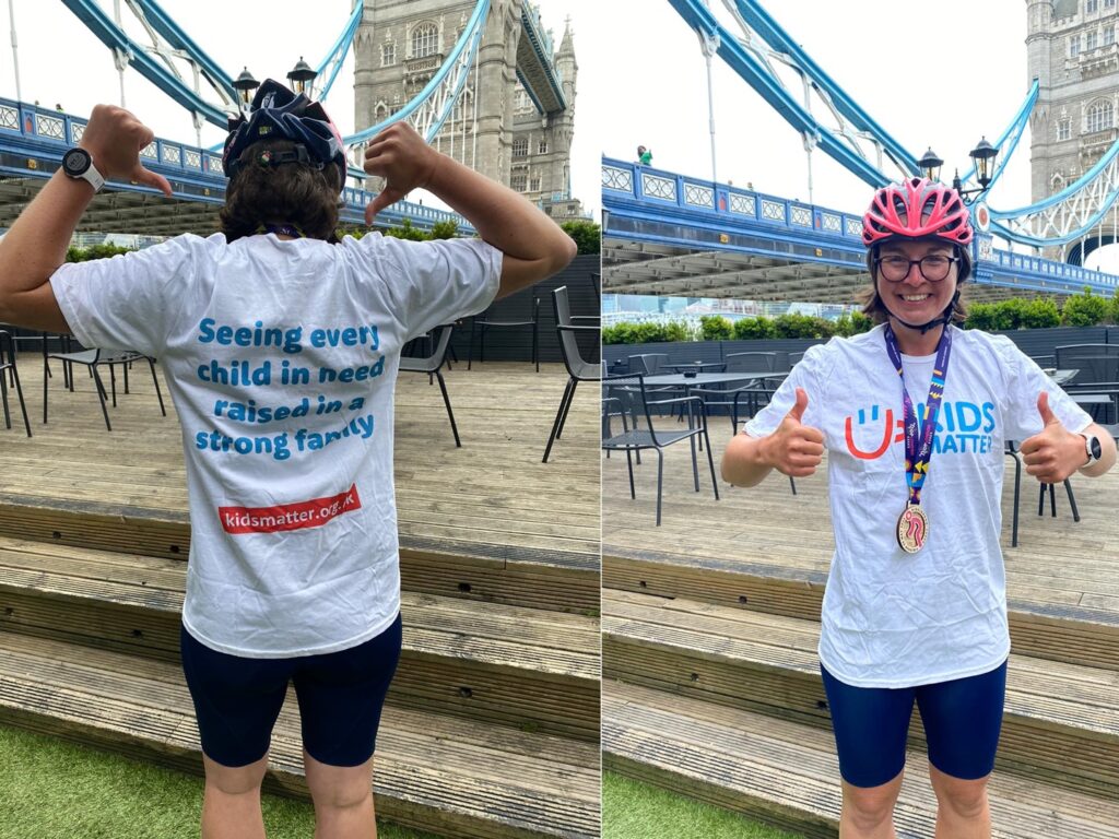 smiling female cyclist standing in front of Tower Bridge after Kids Matter fundraising event
