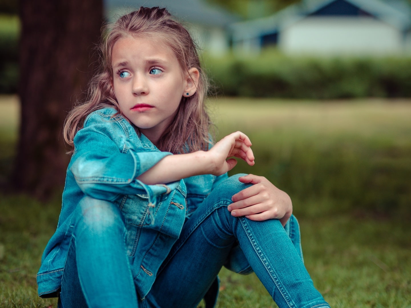 sad girl in blue denim sitting in a park