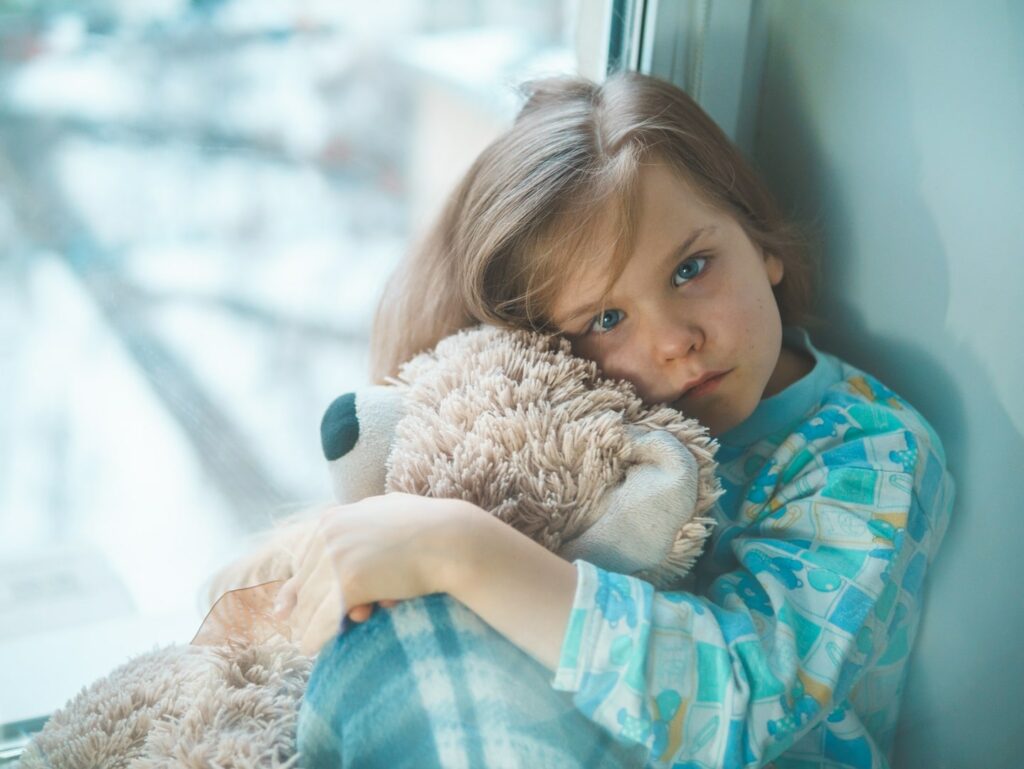 little girl with blue eyes cuddling fluffy teddy bear