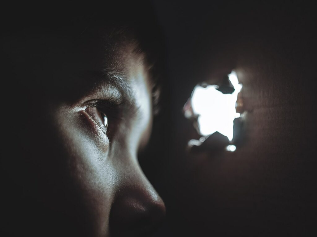close up of little boy in a cupboard looking through peep hole
