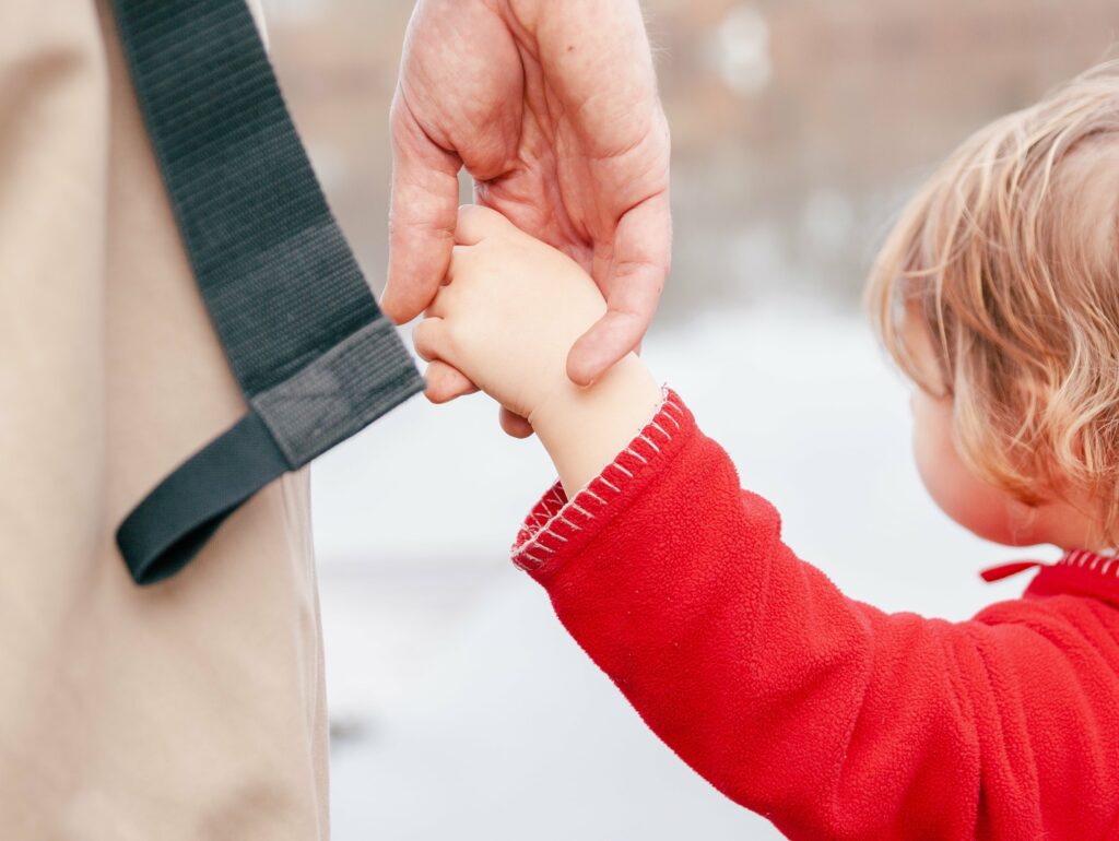 Child dressed in red holding man's hand