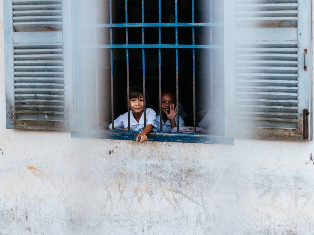 happy children looking through barred window