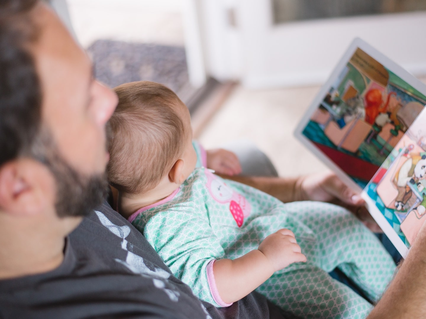 dad reading a story to a baby sitting in his lap