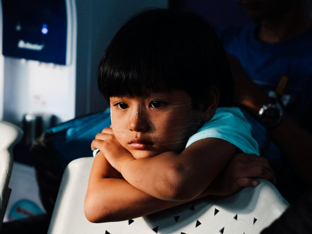 little girl leaning on chair with arms folded