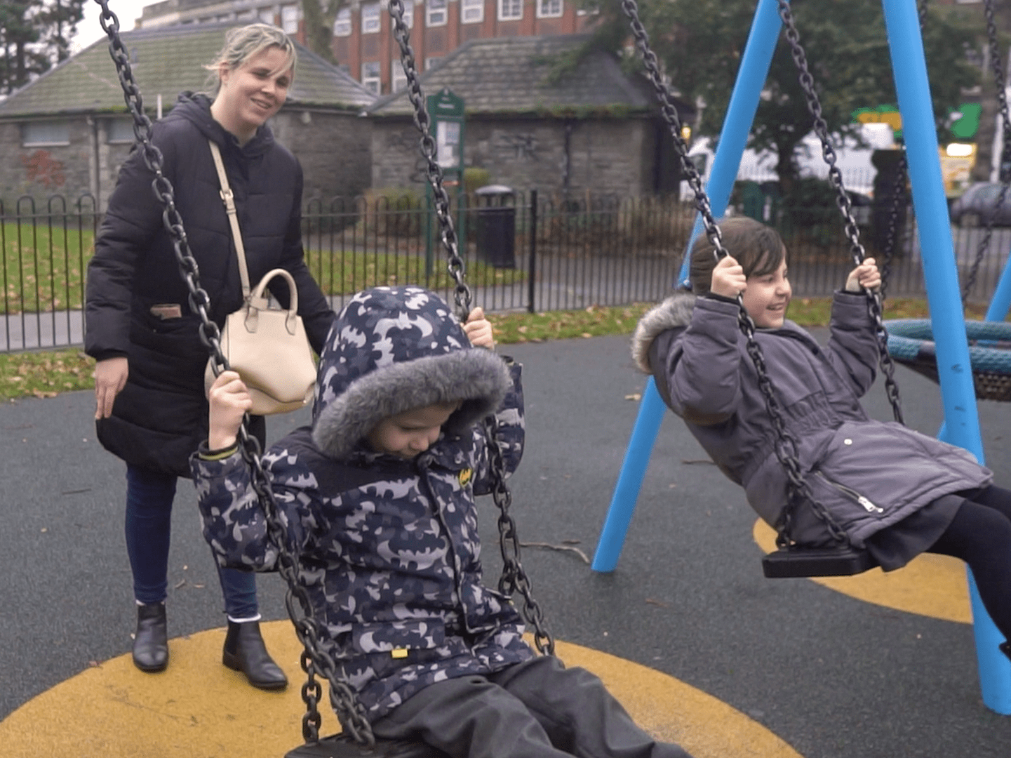 mum pushing children on swings