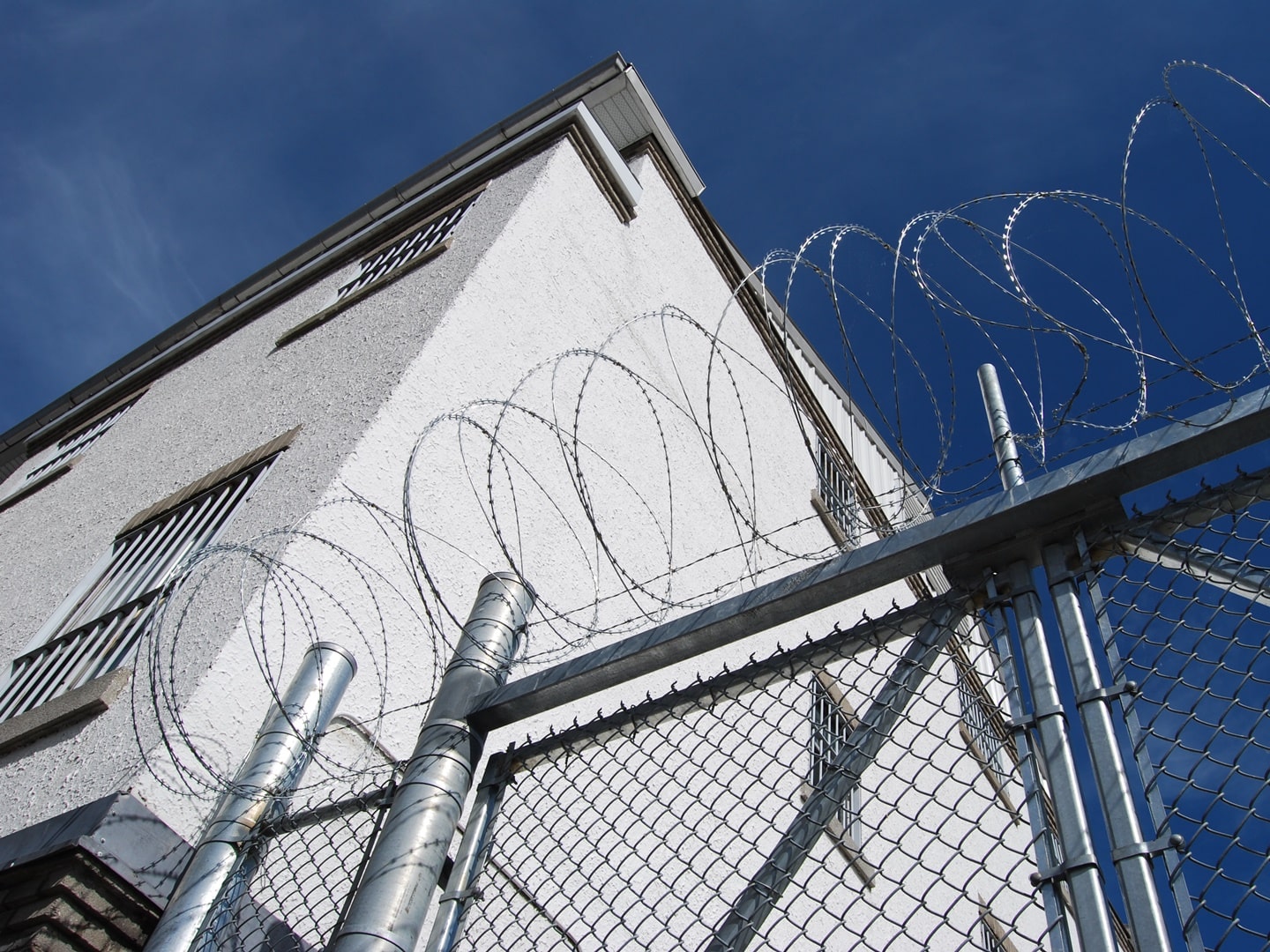 high prison wall with barbed wire fencing