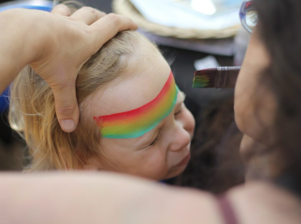small child with rainbow face paint