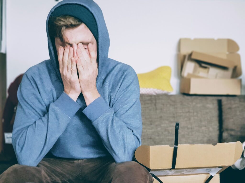 tired man in blue hoodie with head in hands